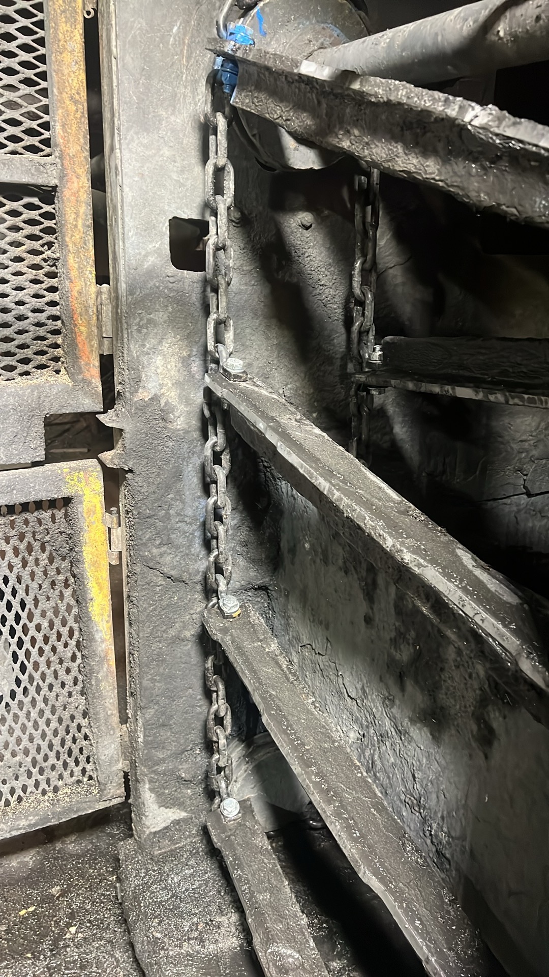 Close-up of chain-supported industrial wear plate and heavy equipment repair area