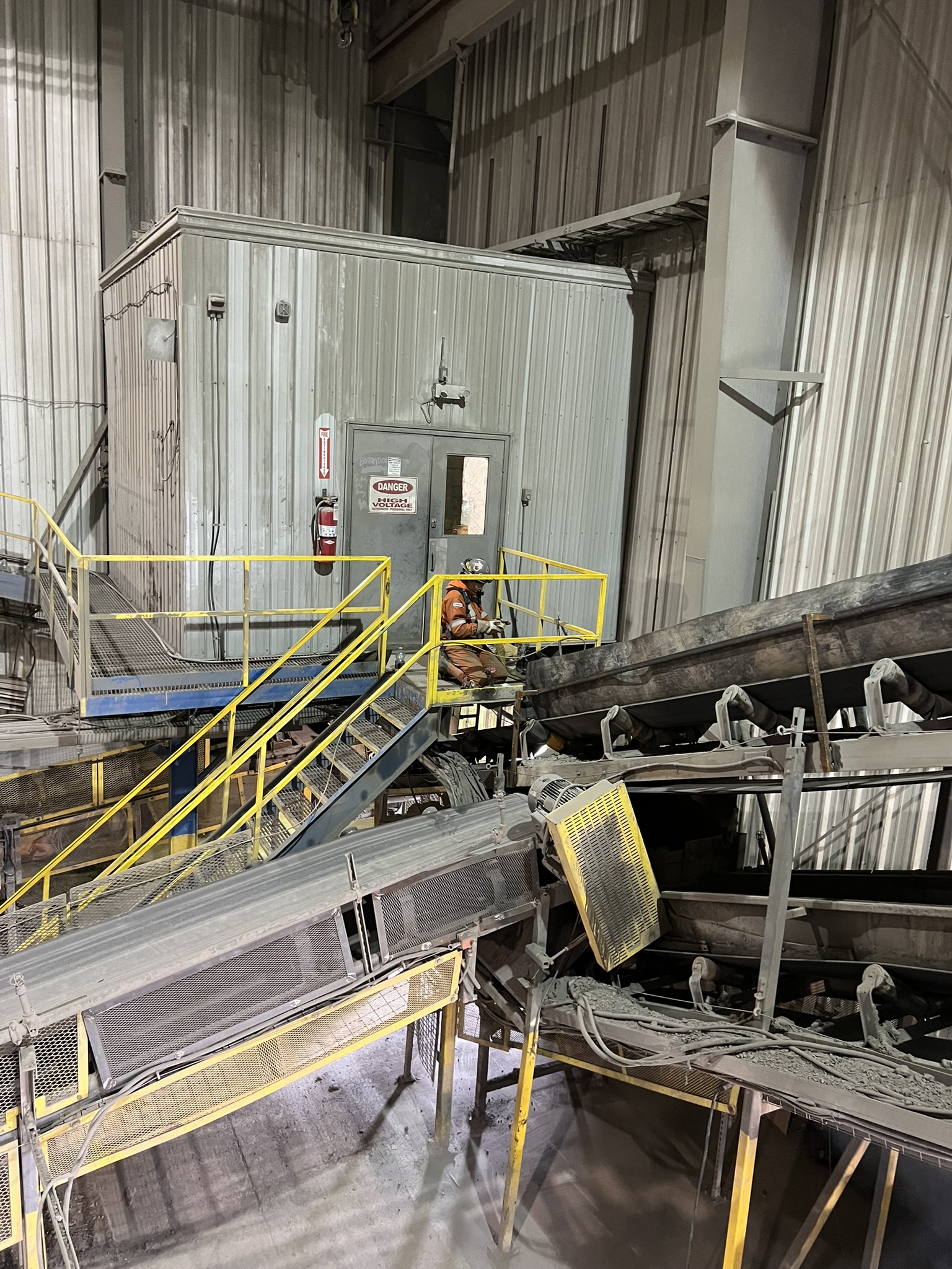 JTR worker performing repair work beside conveyor systems inside an industrial plant